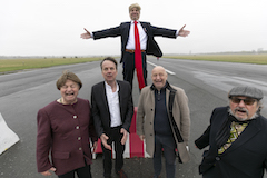 Querformat: Hannes Heesch, etwas erh&ouml;ht, als Donald Trump im Anzug. Er breitet die Arme aus. Vor ihm, etwas tiefer, stehen Christoph Jungmann, Bov Bjerg, Horst Evers und Manfred Maurenbrecher und schreien ihre Verzweiflung heraus.